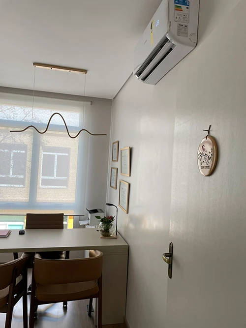 Detalhe do consultório, com mesa de atendimento e luminária